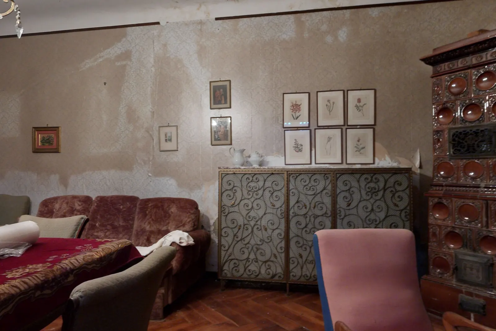 Salon z lončeno pečjo. Tapeta odstopa in jo bo treba obnoviti