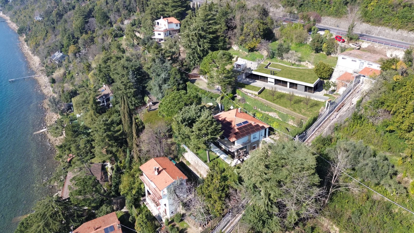 AI simulation of the same view with the planned villa: one storey with a glazed front and a lawn roof, in place of the shed