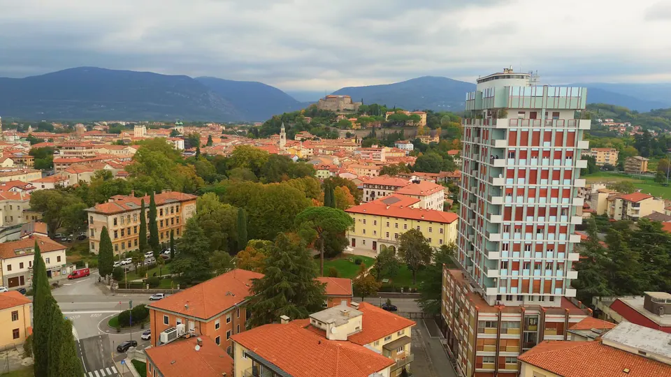 A destra la torre di Via Vittorio Veneto sopra i tetti di Gorizia; a sinistra, sul colle, il Castello, e dietro i monti.